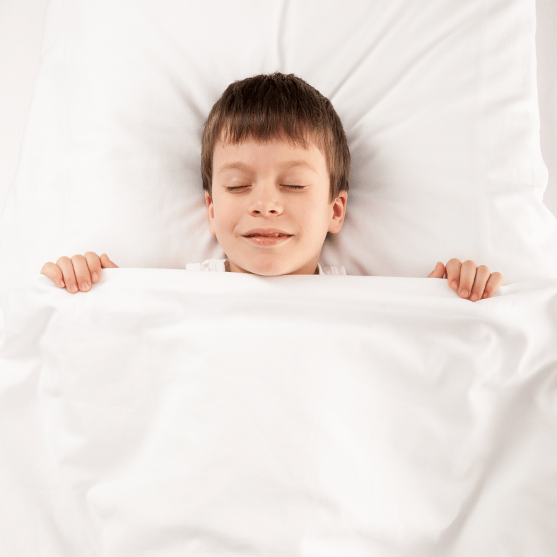 a happy relaxed boy laying in bed 